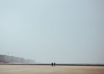 People on beach against clear sky