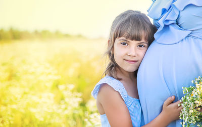 Portrait of cute girl touching belly of pregnant woman