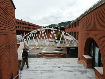 Man cycling on bridge against sky