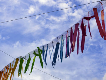 Low angle view of flags hanging on rope against sky