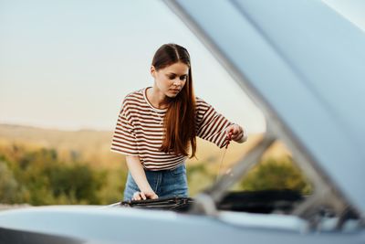 Portrait of young man standing against car