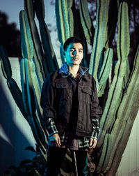 Portrait of young man standing against plants