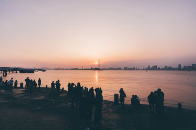 Silhouette people at beach against clear sky during sunset