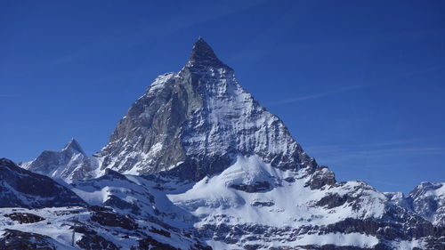 Snow covered mountain against blue sky