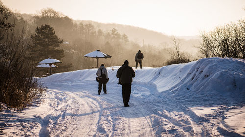 Rear view of people walking on snow covered mountain