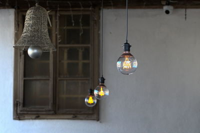 Low angle view of illuminated light bulb hanging on ceiling