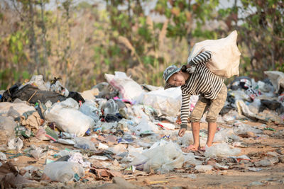 Rear view of people standing by garbage