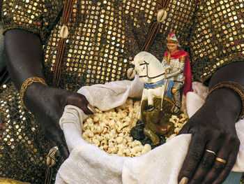 Mother of candomble saint holds a basket with popcorn and the image of saint george ogum