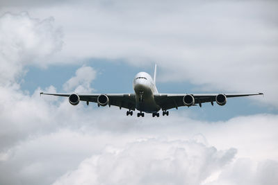 Huge airplane flying through clouds. plane approaching during landing at airport on sunny day.