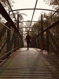 Rear view of man walking on footbridge