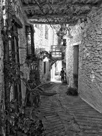 Rear view of woman walking on narrow alley amidst buildings