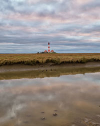 Lighthouse by sea against sky