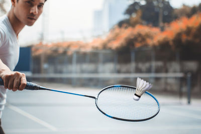 Portrait of young man playing badminton on sports court