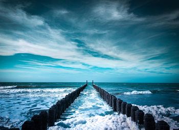 Wooden pier in sea against sky