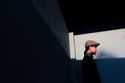 Side view of man standing against wall