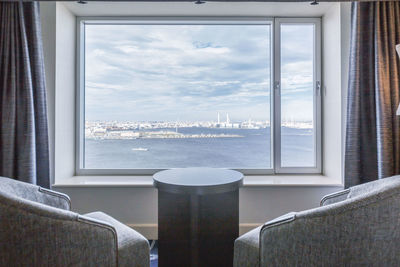 Glass of table by sea against sky