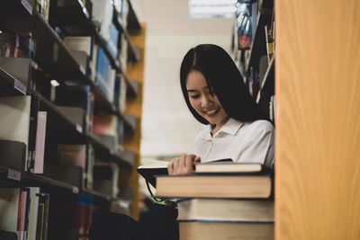 Young woman reading book in library