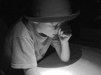 Close-up of tensed boy wearing hat in darkroom