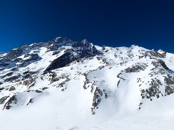 Snow covered mountain against clear blue sky