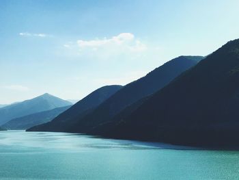 Scenic view of sea and mountains against blue sky