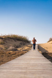 Rear view of man standing on footpath against sky