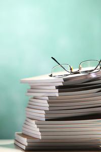 Stack of books with eyeglasses at classroom against blackboard