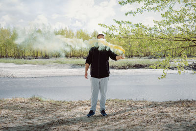 Man with distress flare standing against lake