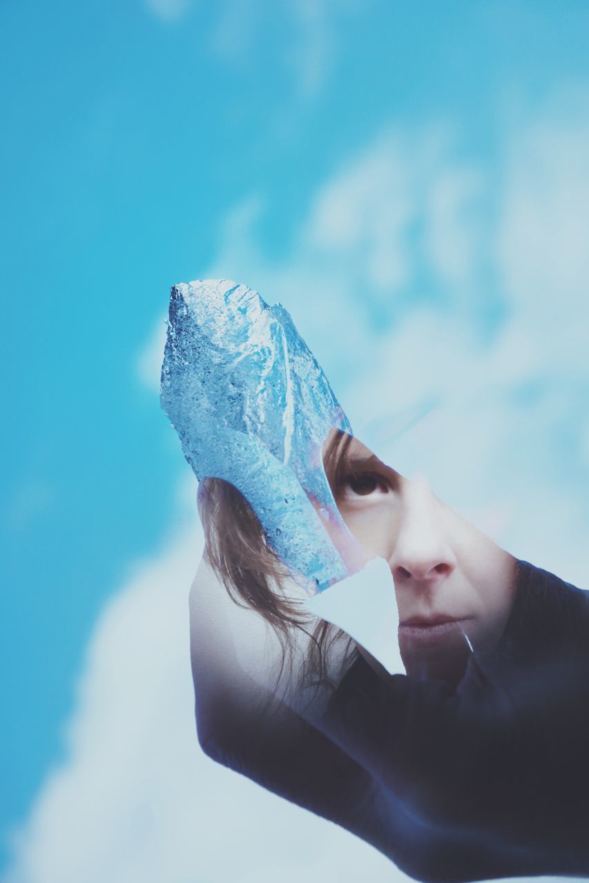 PORTRAIT OF TEENAGE GIRL HOLDING ICE AGAINST BLUE SEA