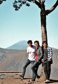 Portrait of friends on mountain against sky