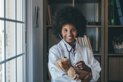 Smiling doctor examining stuffed toy at clinic