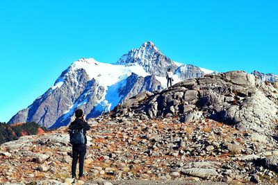 Rear view of person standing on rock against sky