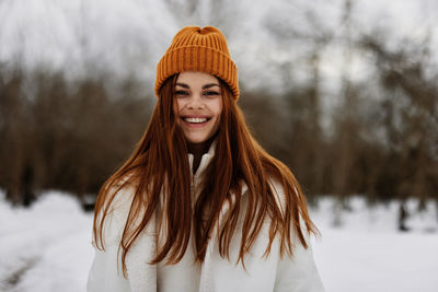 Portrait of young woman standing against trees during winter