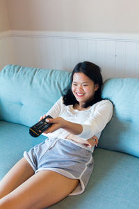 Smiling young woman sitting on sofa