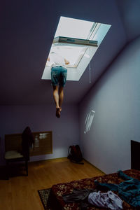 Rear view of man hanging in window of loft