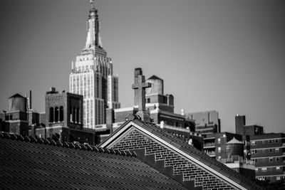 Low angle view of cross on church roof against empire state building in manhattan