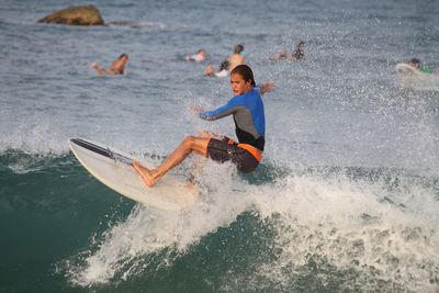 Teenager surfing on wave in sea