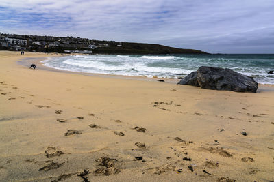 View of calm beach against cloudy sky