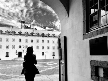 Rear view of woman standing by historic building