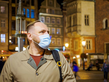 Adult man wearing mask walking in a night european city. mask is a necessary in new normal reality