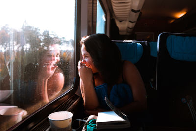 Woman looking through window while sitting in bus