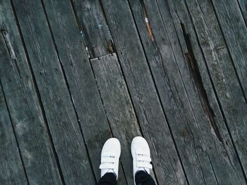 Low section of person standing on wooden floor