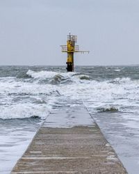 Lighthouse by sea against clear sky