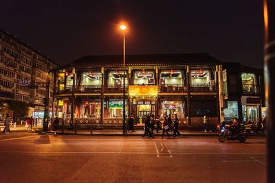 People walking on illuminated city street at night