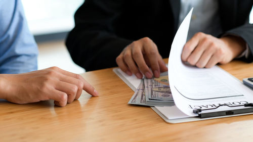 Midsection of man holding hands on table