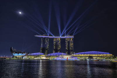 Illuminated bridge over river at night