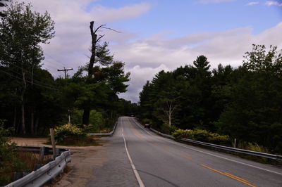 Road amidst trees against sky