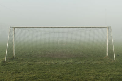 Sports net on grassy field during foggy weather