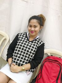 Portrait of smiling young woman sitting on chair