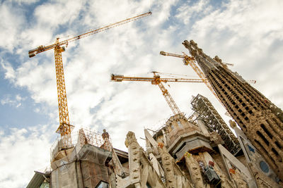 Low angle view of cranes against sky