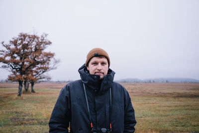 Portrait of man standing on field against sky during winter